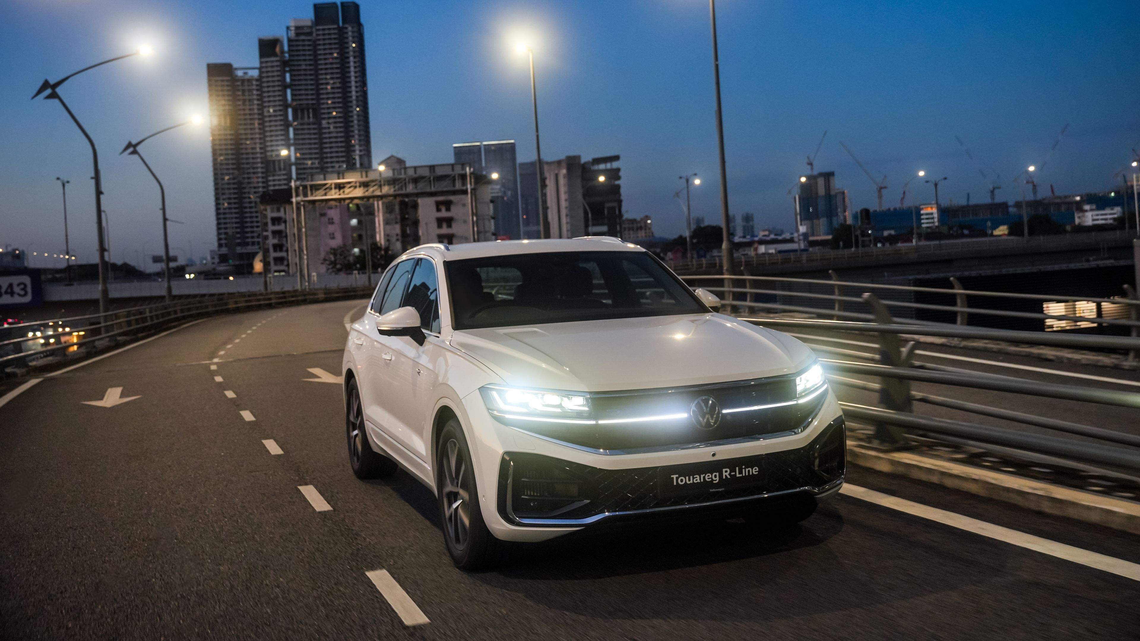 Volkswagen Touareg R-Line A Volkswagen Touareg R-Line, a luxury SUV, driving on a city road during dusk.