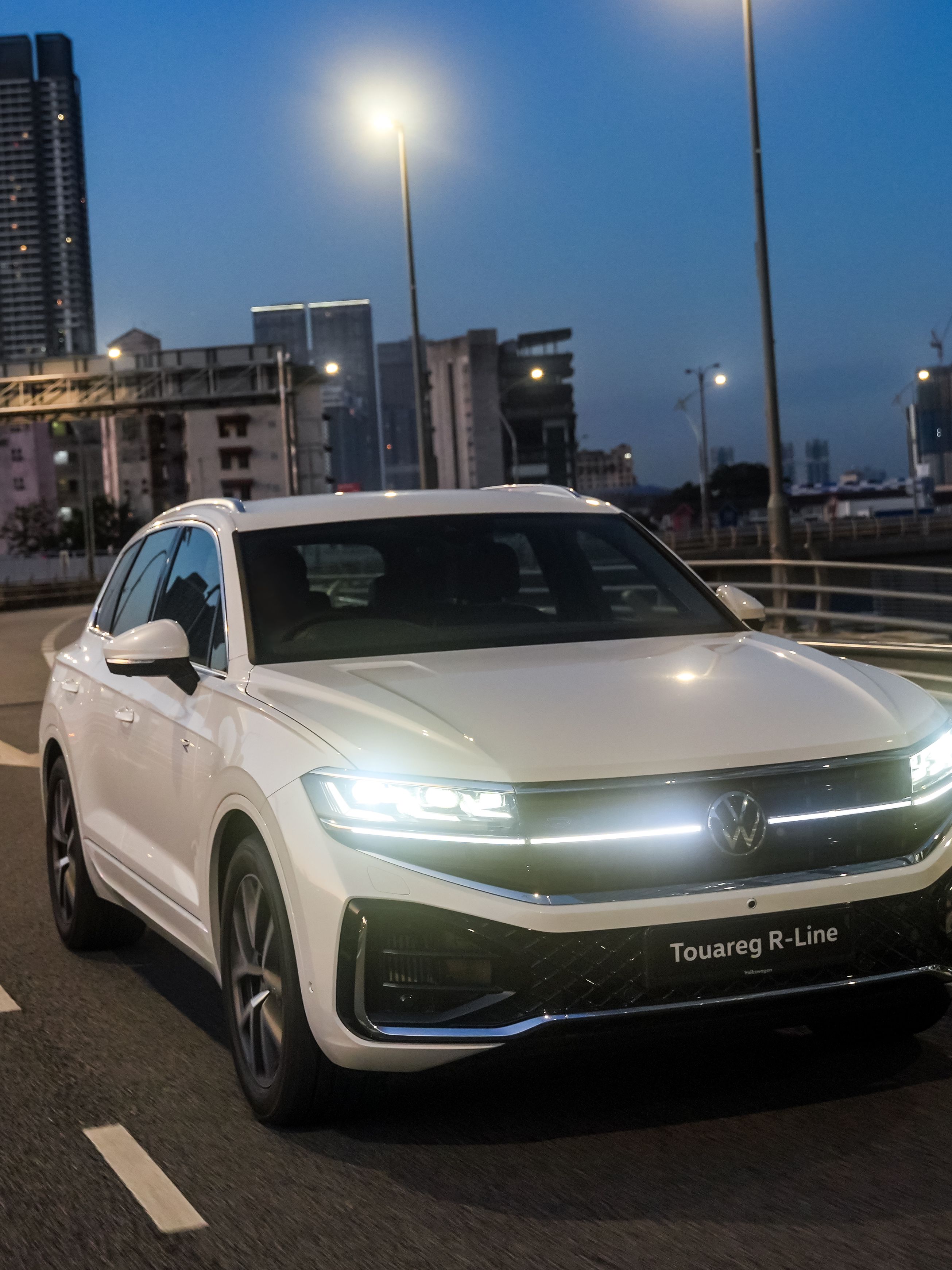 Volkswagen Touareg R-Line A Volkswagen Touareg R-Line, a luxury SUV, driving on a city road during dusk.